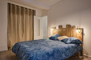 um quarto com uma cama azul e uma cabeceira em madeira em Magnifique T3 centre ville avec WIFI RDC em Limoux