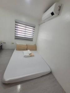 Zimmer mit einem großen weißen Bett und einem Fenster in der Unterkunft Budget friendly yet cozy staycation in Calapan