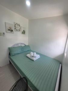 ein kleines Zimmer mit einem grünen Bett und zwei Handtüchern in der Unterkunft Budget friendly yet cozy staycation in Calapan