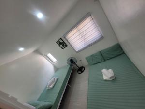 a small bedroom with a green bed and a window at Budget friendly yet cozy staycation in Calapan