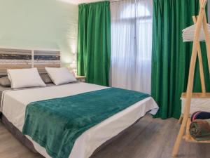 a bedroom with a large bed with green curtains at in front of the pool, large terrace, elegant & confortable, Wi-Fi in Costa Calma +15 photos