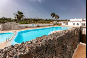 una piscina junto a una pared de piedra en in front of the pool, large terrace, elegant & confortable, Wi-Fi, en Costa Calma