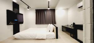een witte slaapkamer met een bed en een televisie bij Daon Hotel Gimhae Injae in Gimhae