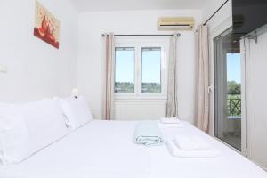 Un dormitorio blanco con una cama blanca y una ventana en Natasha’s home, en Perama