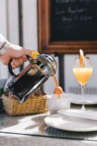 a person pouring an orange juice into a glass at Pariisin Ville in Porvoo