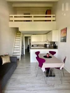 a living room with a table and chairs and a kitchen at Appartement Duplex Climatisé Le Trident in Saintes-Maries-de-la-Mer