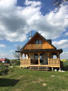 uma grande casa de madeira com um alpendre num campo em Domek na wsi Roztocze Bania Bilard 