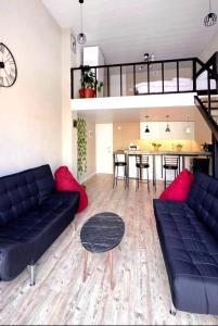 a living room with black couches and a dining room at Duplex guest house in Batroun in Batroûn