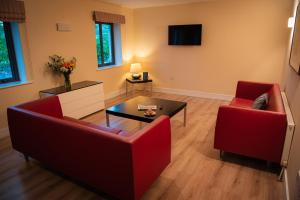 a living room with two red chairs and a table at Castle Dargan Hotel in Sligo