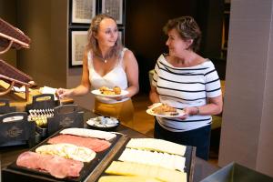 zwei Frauen, die Teller mit Essen in einem Buffet halten in der Unterkunft Landgoed Duin & Kruidberg in Santpoort-Noord