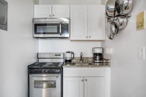 a kitchen with white cabinets and a stove and microwave at Well-located S Boston 1BR on E Broadway BOS-474 in Boston