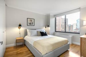 a white bedroom with a bed and a large window at Midtown 2BR w Pool Gym Roof nr Subway NYC-385 in New York
