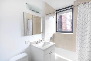 a white bathroom with a sink and a shower at Midtown 2BR w Pool Gym Roof nr Subway NYC-385 in New York +18 photos