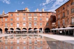 un grande edificio in mattoni con una piscina riflettente di fronte ad esso di Le Montalbanais a Montauban