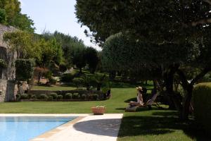 uma mulher sentada numa cadeira ao lado de uma piscina em Malvazia Grand Estate, 4acre Immersed in Greenery, By ThinkVilla em Kermoútsi