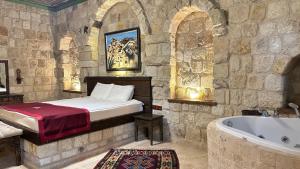 een slaapkamer met een bed en een bad bij Under Cave Cappadocia in Urgup