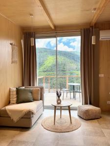 ein Wohnzimmer mit einem Sofa und einem Tisch vor einem Fenster in der Unterkunft Casa Raposa Lodges - Terrace Mountain View in Manteigas
