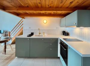 una cocina con armarios azules, un lavabo y una escalera en * Le Grand Hotel * Beau T1 Bis avec vue, en Font-Romeu-Odeillo-Via