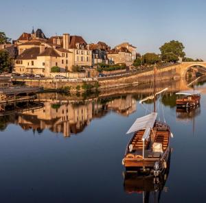 un barco sentado en el agua junto a una ciudad en Columna Historya 1, en Bergerac
