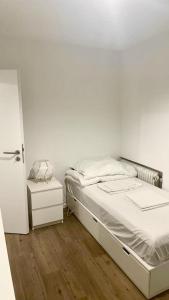Habitación blanca con cama y mesita de noche en Pension RD Reutlingen, en Reutlingen