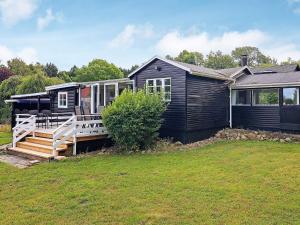 ein schwarzes Haus mit einer Veranda und einem Haus in der Unterkunft Holiday home Holbæk III in Holbæk