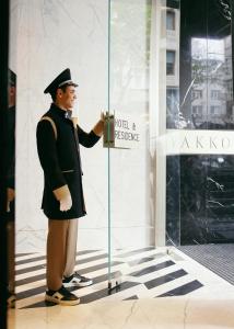 un homme debout devant une porte en verre dans l'établissement Vakko Hotel and Residence, à Istanbul