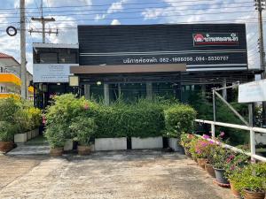 un bâtiment avec des plantes en pot devant lui dans l'établissement Morning Home บ้านหมอนอิง, à Lop Buri