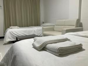 una camera ospedaliera con due letti e una sedia e asciugamani di Morning Home บ้านหมอนอิง a Lopburi