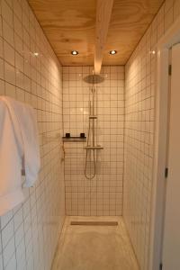 a bathroom with a shower with white tiled walls at Vakantiehuisje Buuf in de Brabantse natuur in Schijndel