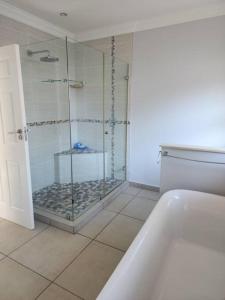 uma casa de banho com um chuveiro e uma cabina de duche em vidro. em NorthShore Beach House em Southbroom