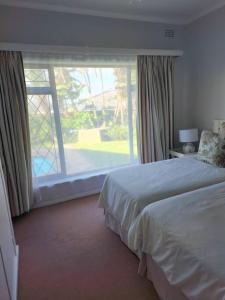 um quarto com uma cama e uma grande janela em NorthShore Beach House em Southbroom