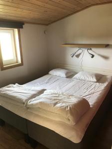 ein großes weißes Bett in einem Schlafzimmer mit Fenster in der Unterkunft Svalsjöns Stugor Öland in Köpingsvik