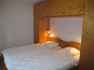 1 dormitorio con 1 cama blanca grande y cabecero de madera en Residenz Plein Ciel, Wohnung CAPRICORNE VEYS240 en Veysonnaz