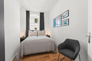 a bedroom with a bed and a chair at The Straßburger, stylish 3 BR apartment in Mitte, group & family friendly, 4- 6 Guests in Berlin +9 photos
