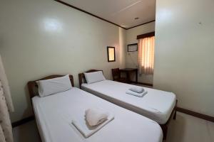 two beds in a room with white sheets and towels at Tenzai Homestay in Puerto Princesa City
