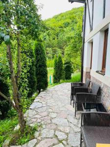 a stone walkway with benches and a tree next to a building at Azra River View House in Bihać