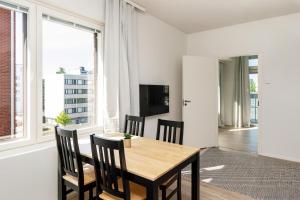 a dining room with a wooden table and chairs at Kotimaailma Apartments Loimu V in Oulu