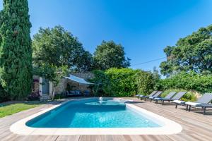 - une piscine dans un jardin avec 2 chaises longues et une piscine dans l'établissement Mazet Pierre de Vers - Le Mas des Olivers Nîmes, à Nîmes