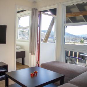 a living room with a couch and two windows at Hafjell Alpinlandsby Pluss in Hafjell