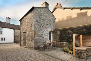 Wharton House Mews in Cartmel, Lake District في كارتميل: فناء مع طاولة وكراسي بجوار مبنى