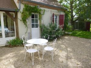 una mesa blanca y sillas frente a una casa en Les volets rouges en Sémoy