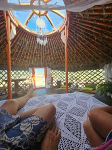 a person laying on a bed in a straw hut at Yurta Bora Bora in L'Ametlla de Mar