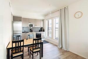 cocina con mesa, sillas y reloj en Kotimaailma Apartments Loimu IV en Oulu