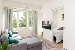 a living room with a couch and a tv and a bed at Kotimaailma Apartments Loimu IV in Oulu