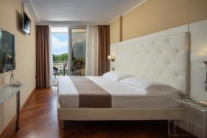 Hotel Savoy Palace - TonelliHotels في ريفا ديل غاردا: غرفة نوم بسرير ابيض كبير وبلكونة
