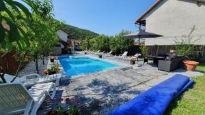 a pool with chairs and a person sitting on a couch next to it at Ati&Hanna in Praid