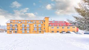 an orange building with snow in front of it at Hotel Traumblick in Oberhof