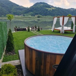 una bañera de hidromasaje en el césped junto a un lago en Unique Lake House Paradiso, en Zvornik