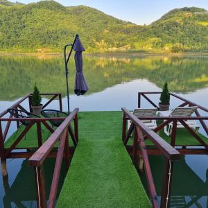 einen Blick auf einen See mit zwei Tischen und einem Sonnenschirm in der Unterkunft Unique Lake House Paradiso in Zvornik