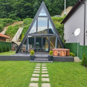 ein Haus mit einem dreieckigen Fenster und einem Steinweg im Hof in der Unterkunft Unique Lake House Paradiso in Zvornik